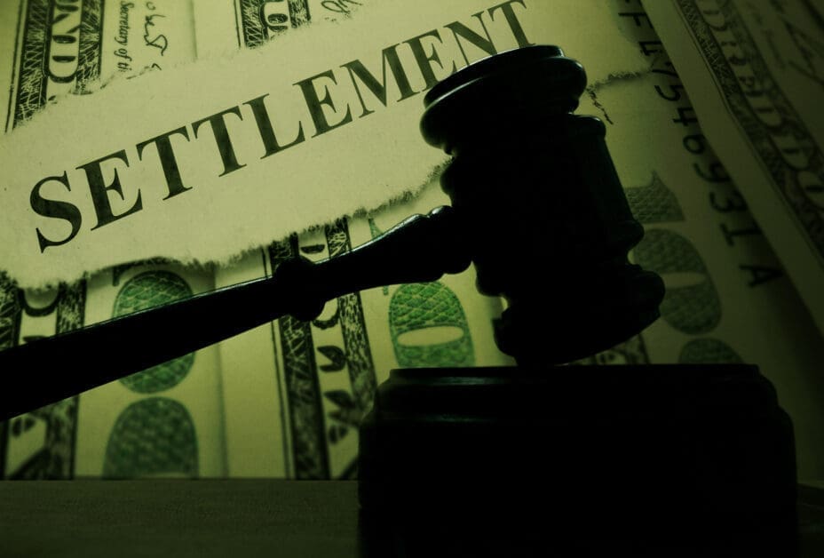 Silhouette of a Judge's Gavel over a Torn Paper with 'settlement' and Dollar Bills, Implying Legal Financial Settlement.