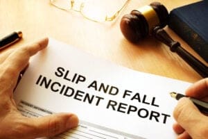 Close-up of a Hand Filling out a 'slip and Fall Incident Report' Form with a Pen and a Wooden Gavel Nearby.