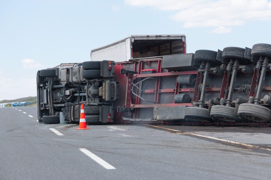Overturned Semi-trailer Blocking a Highway with an Orange Traffic Cone Nearby, Under a Clear Sky