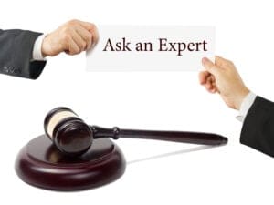 Two Hands Exchange a Card Reading 'ask an Expert' with a Judge's Gavel in the Foreground, Implying Legal Advice.