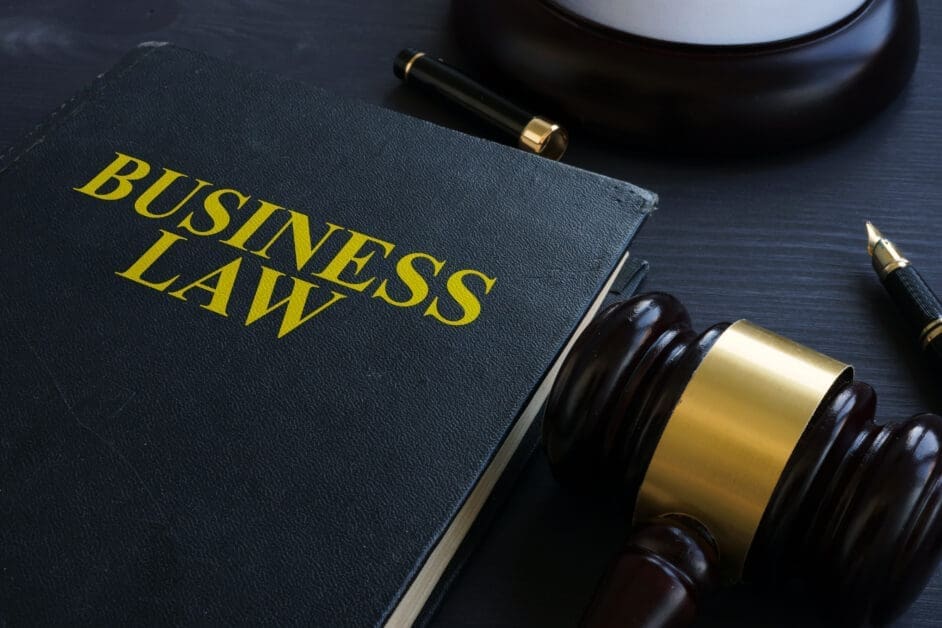 Close-up of a Dark Notebook Labeled 'business Law' in Gold on a Desk, with a Gavel and Fountain Pen Nearby.