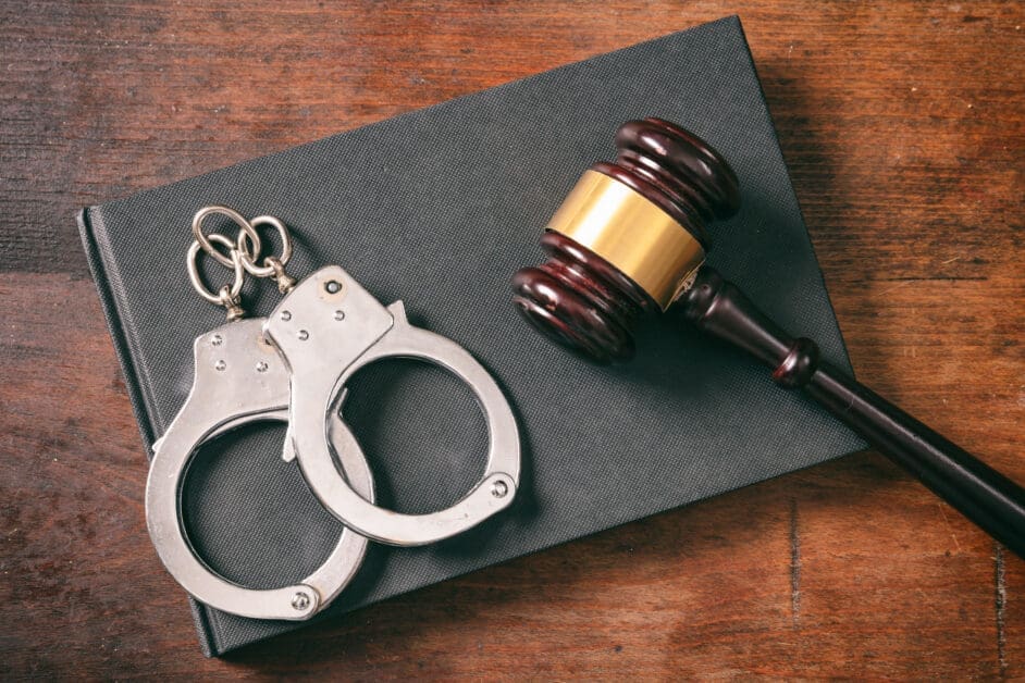 - Attorneys.Media - Legal Expert Interviews & Trusted Advice Handcuffs, a Gavel with Brass Band, and a Notebook on a Wooden Desk.